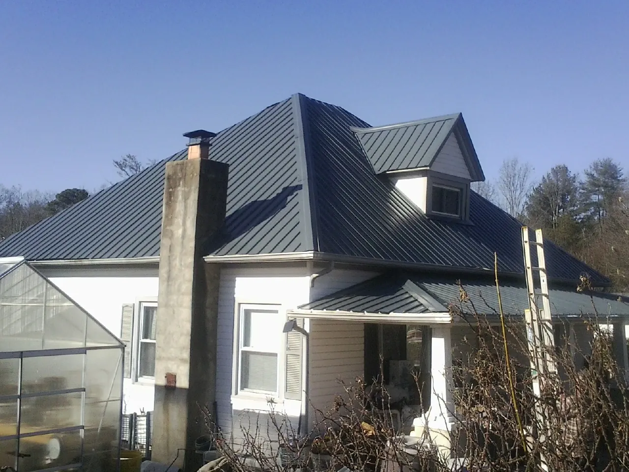 Dark blue standing seam metal roof on a white farmhouse with dormer — Slate & Tile Roof Repair by Roofing Brothers in Kimmswick