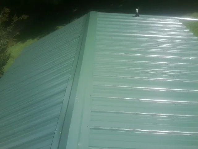 New green metal panels meeting at the ridge of a roof — Flat Roof Repair work by our crew in Kimmswick