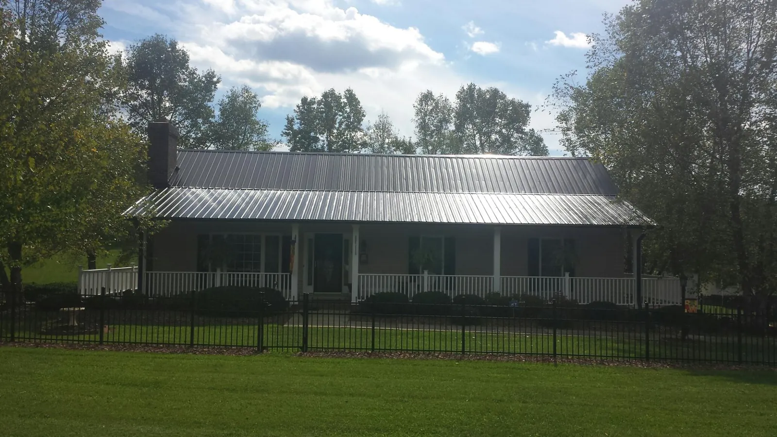 Gray metal roof on a brick ranch with a full width front porch — Gutter Guard Installation work by our crew in Kimmswick